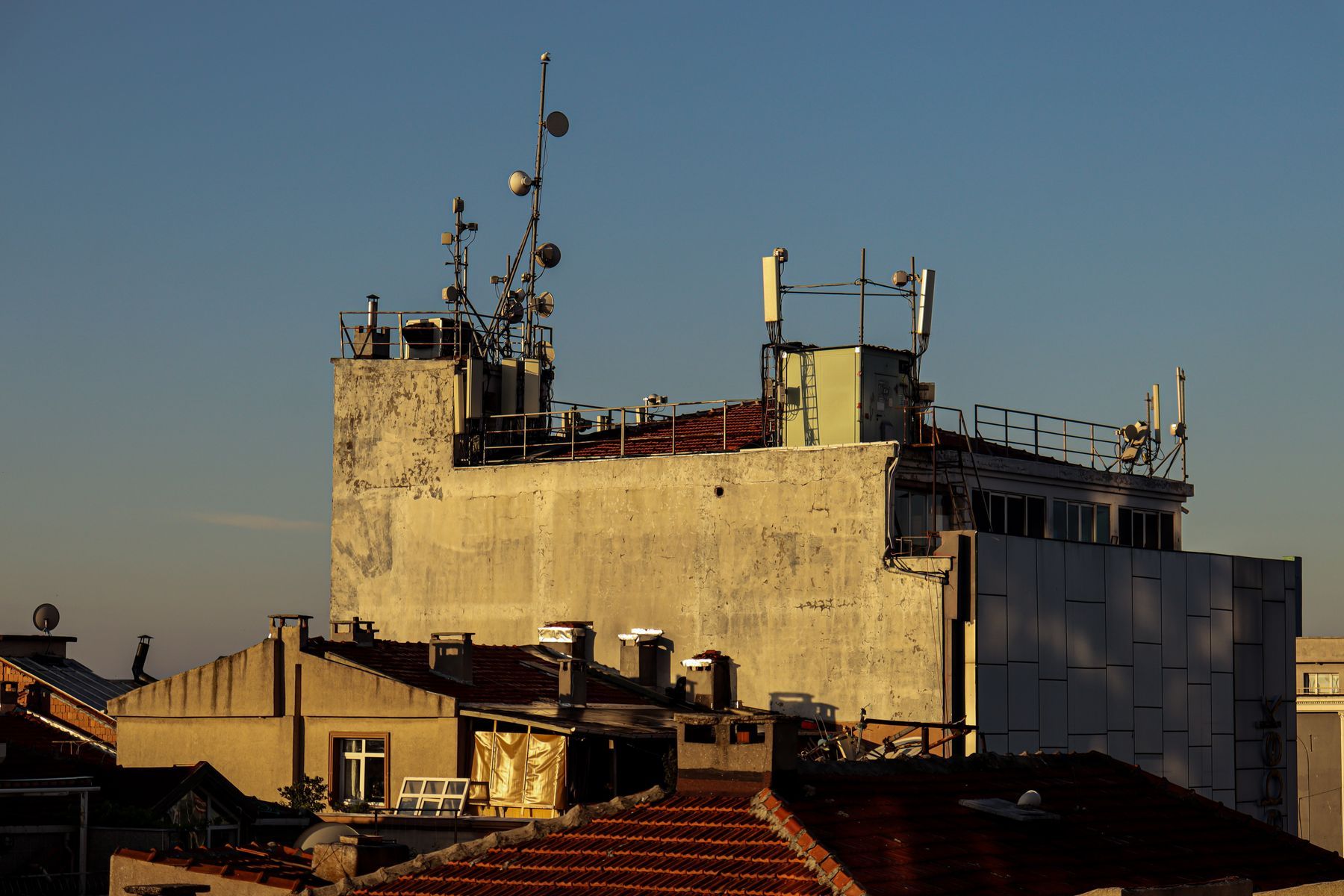 Cellular panel antennas, dishes and equipment cabinets on a commercial building rooftop