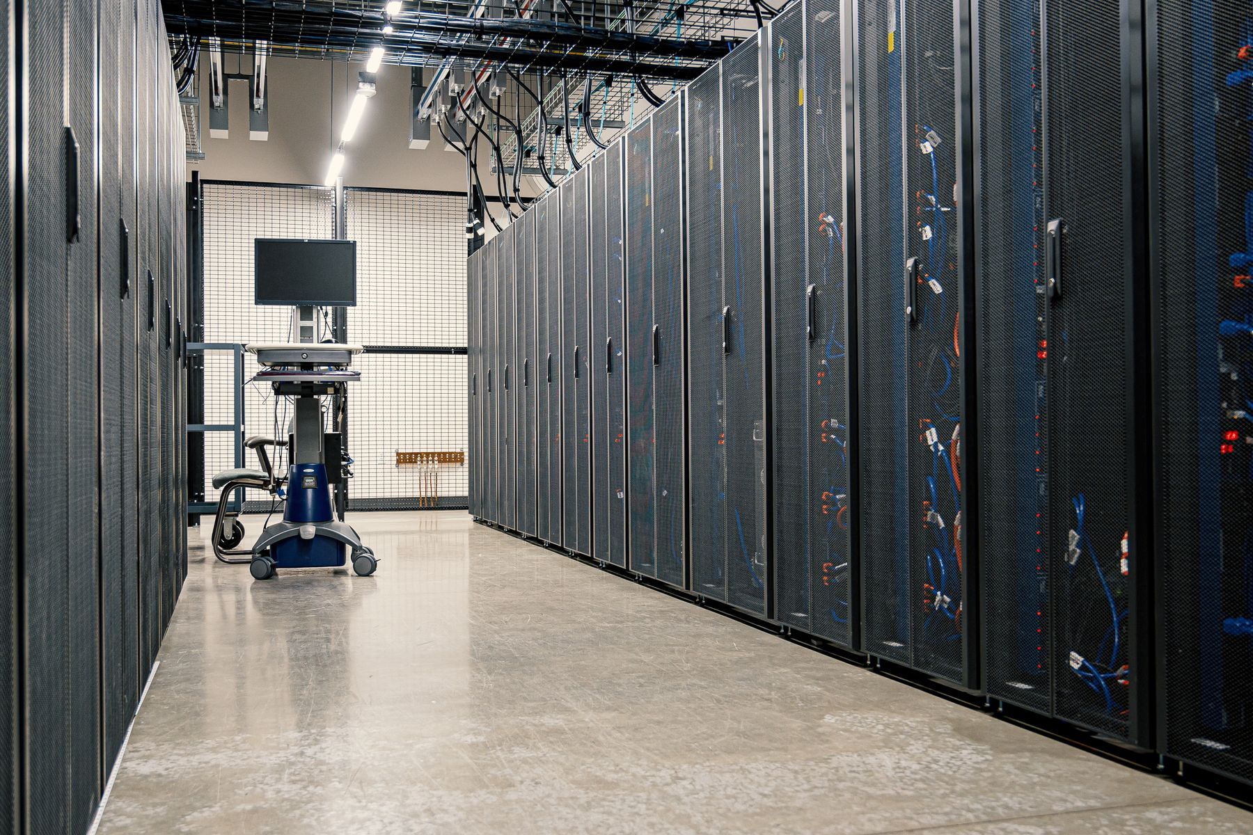 Data center aisle lined with tall server cabinets and an equipment cart