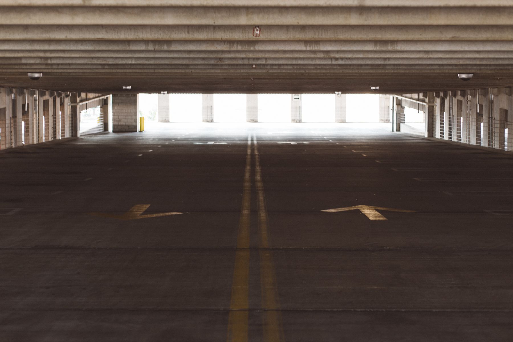 Empty concrete parking structure deck with painted directional arrows