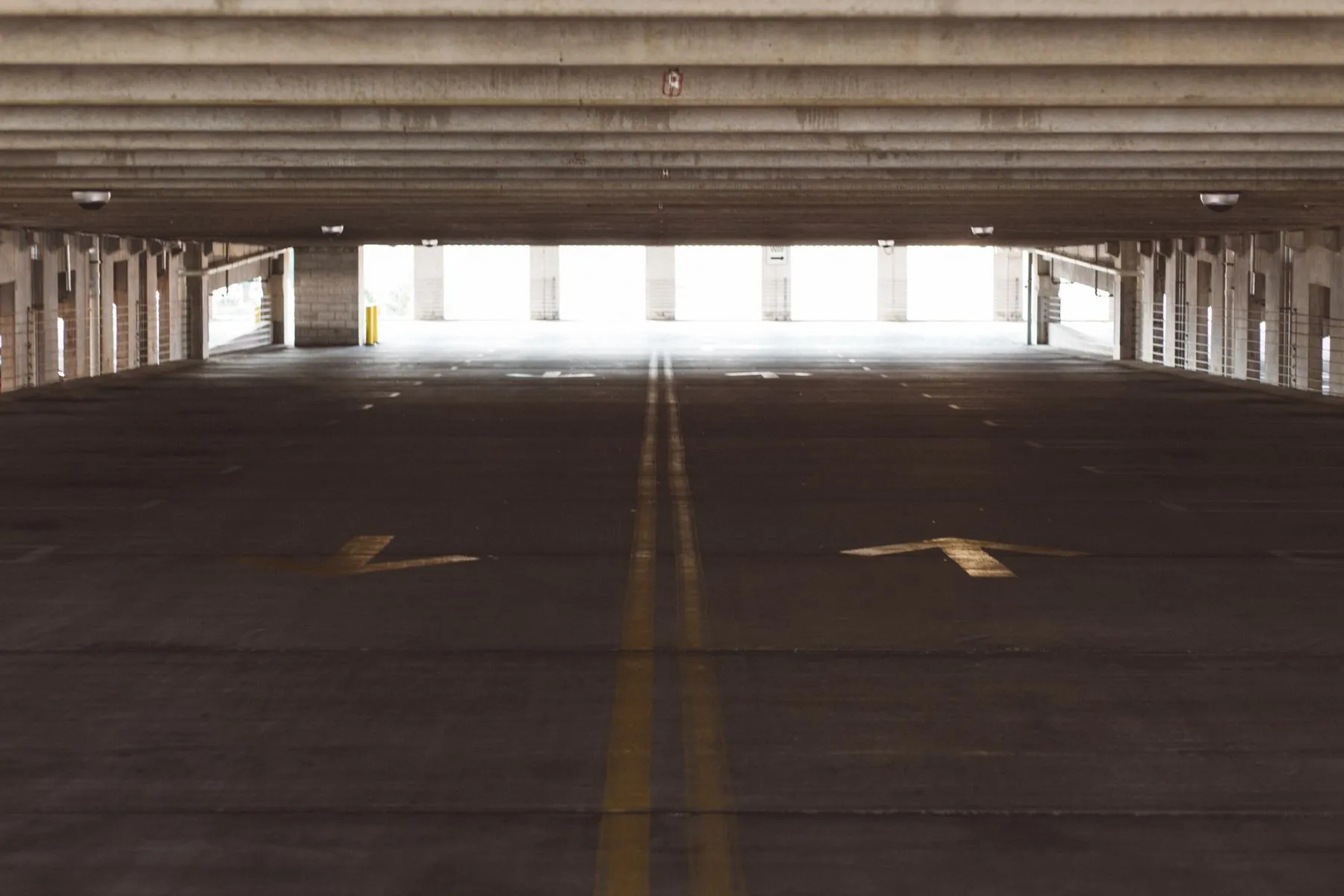 Empty concrete parking structure deck with painted directional arrows