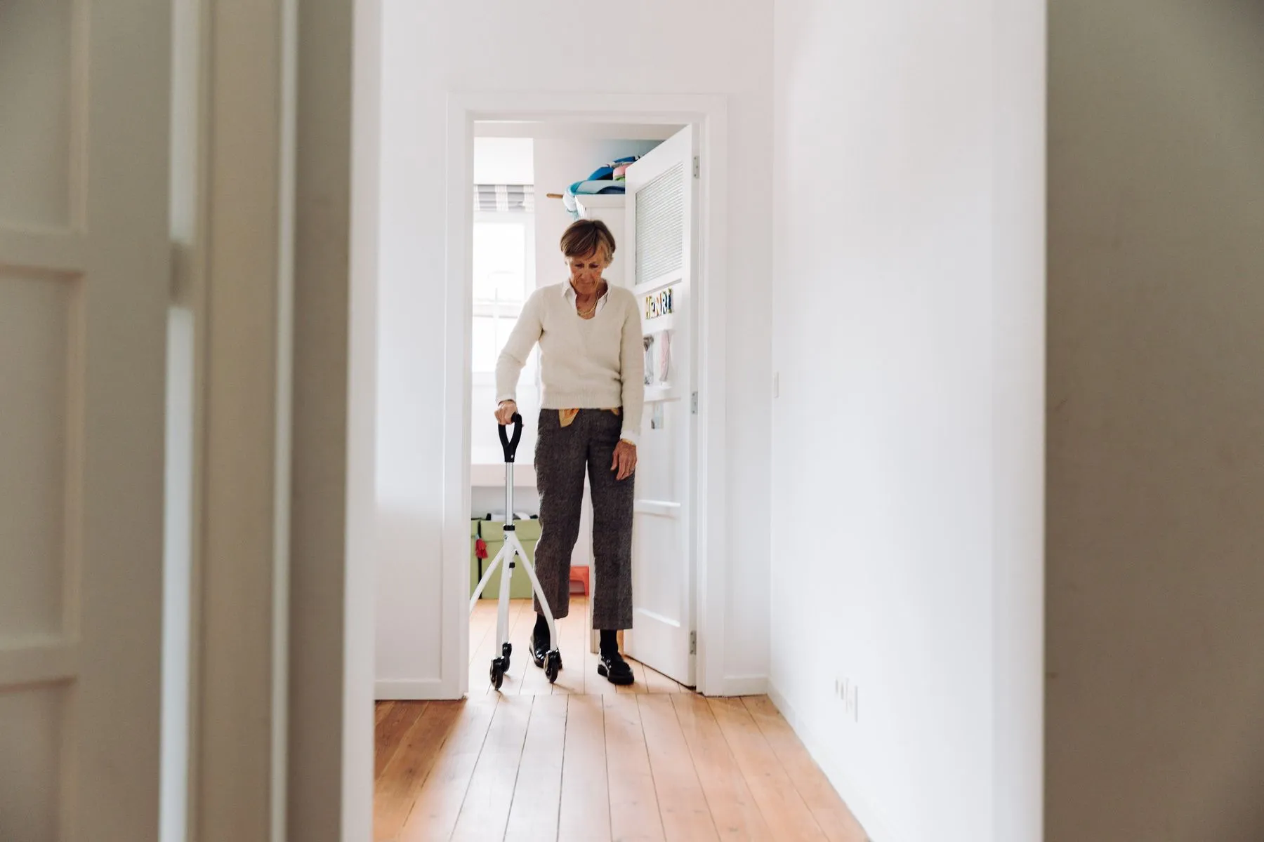 Resident using a rollator in a sunlit hallway