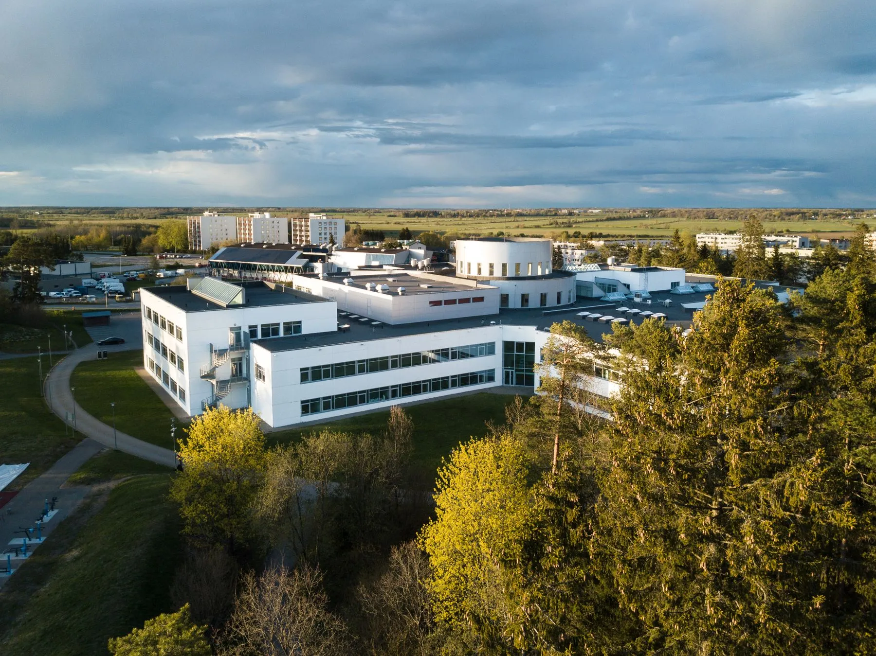 Aerial view of a modern college campus building complex surrounded by trees