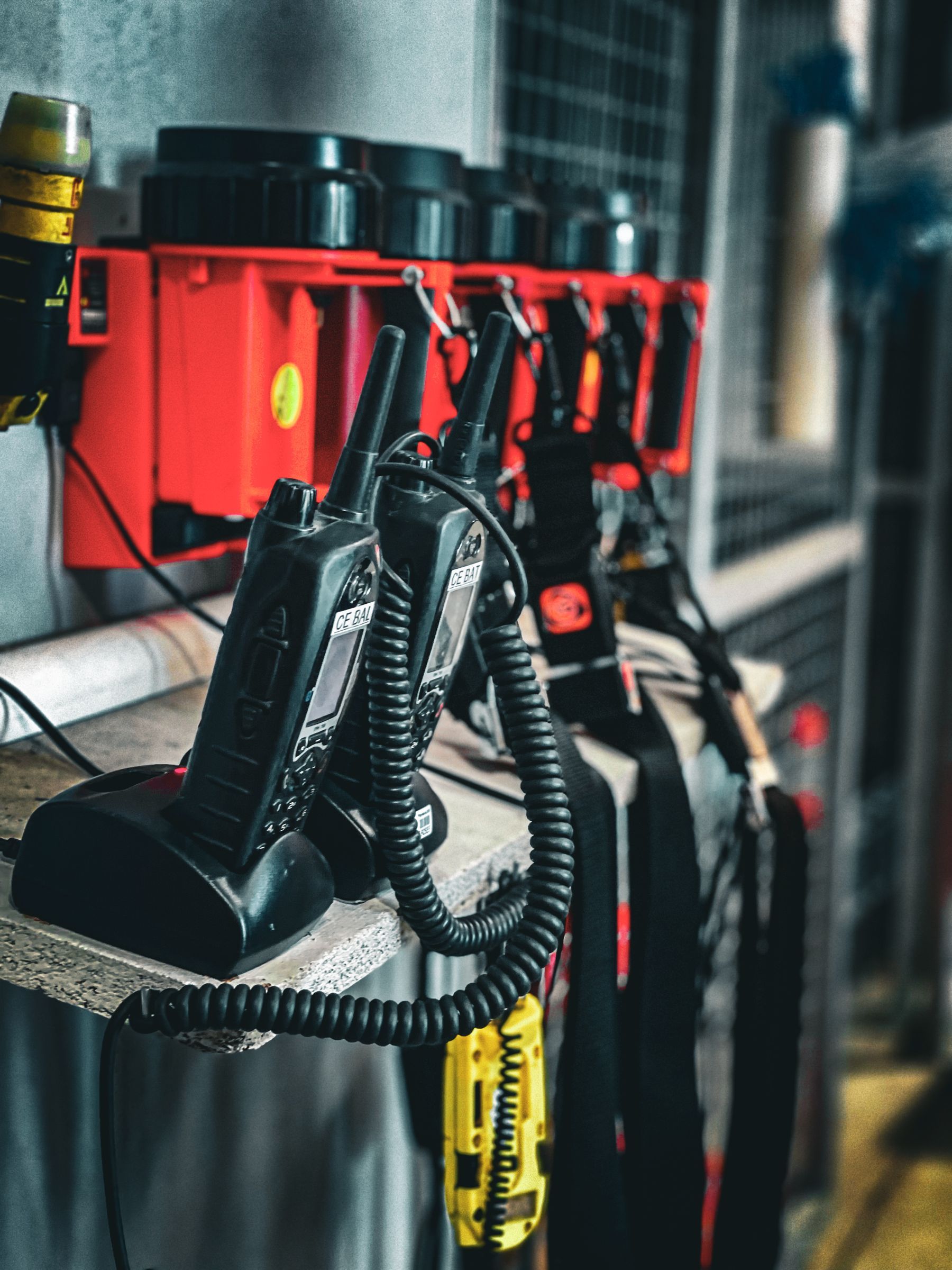 Portable two way radios on a charging rack with spare batteries and speaker microphones