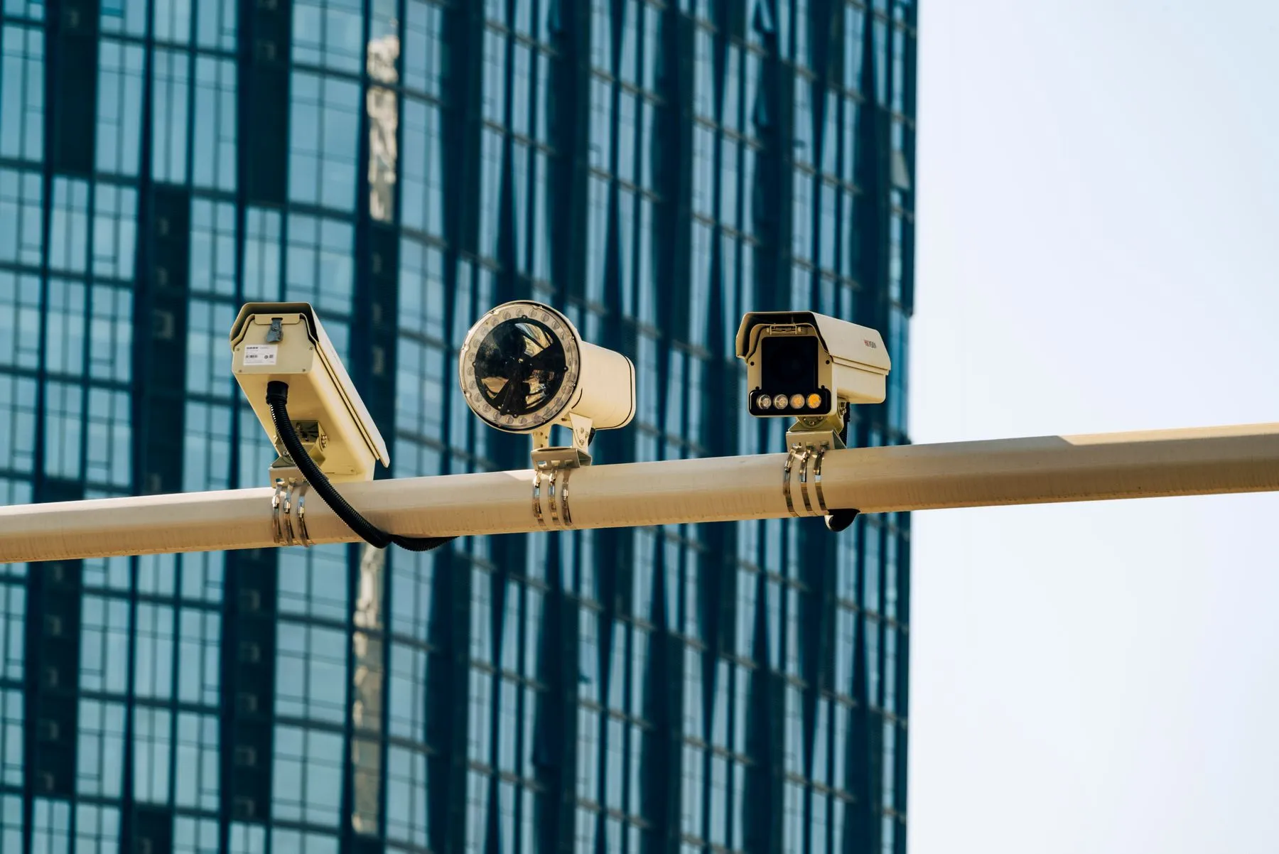 Surveillance cameras mounted on a pole in front of a glass office building