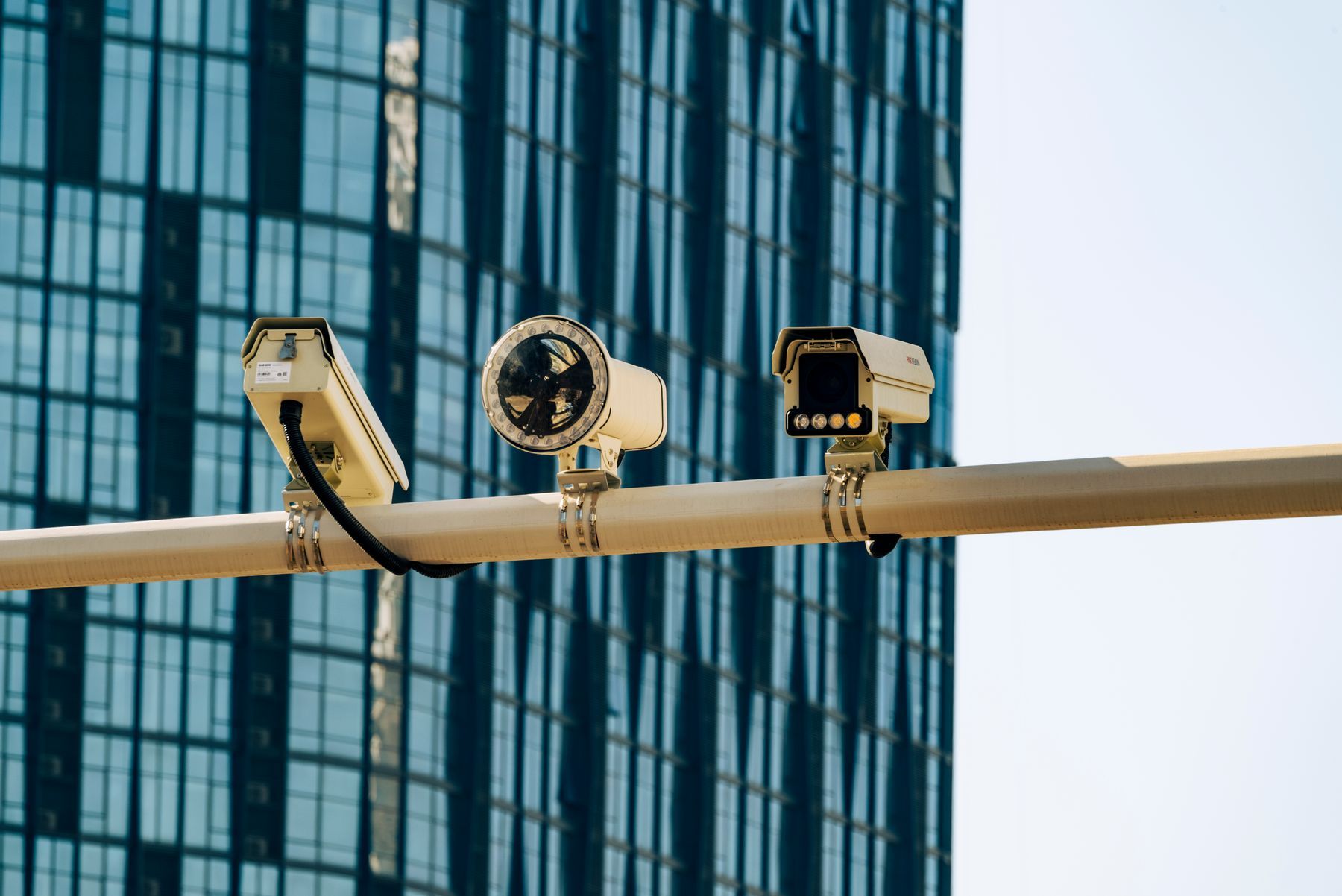 Surveillance cameras mounted on a pole in front of a glass office building