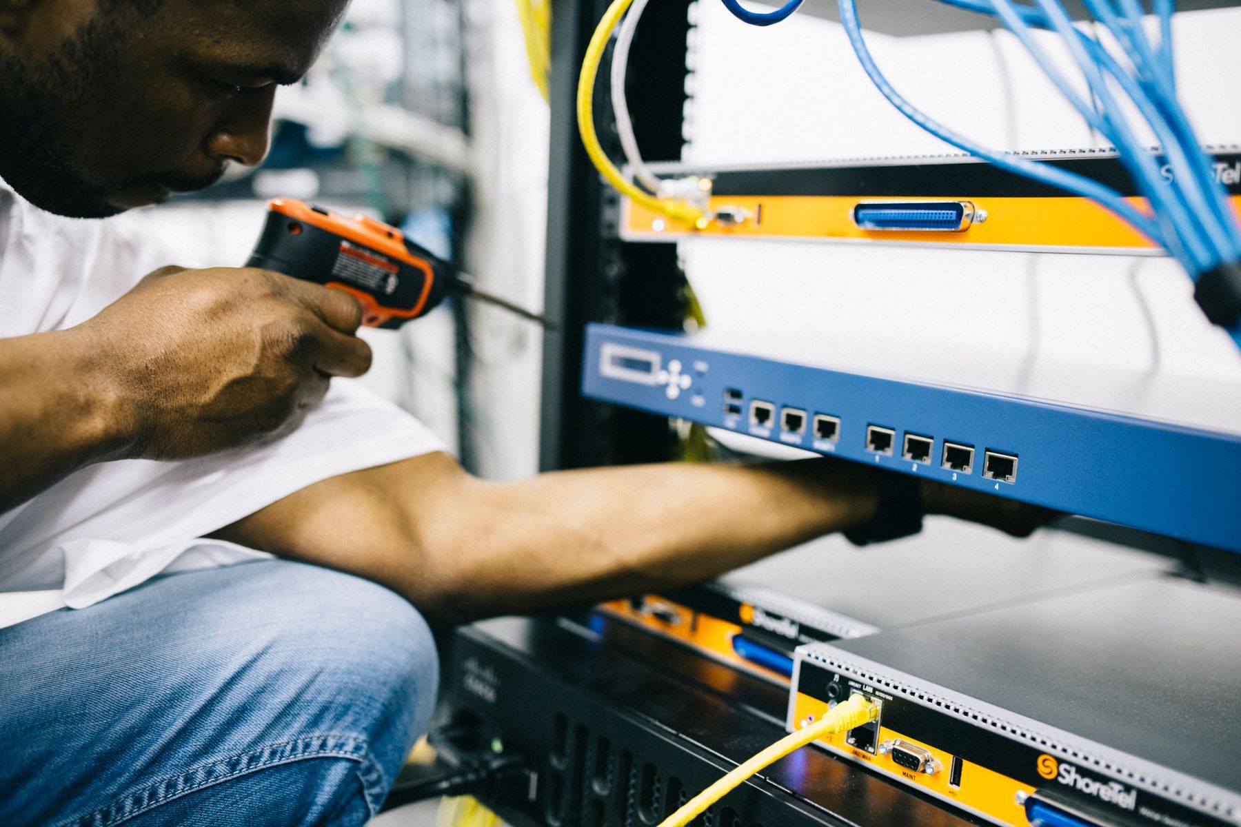 Technician with a hand tool working on the ports of a rack mounted network switch