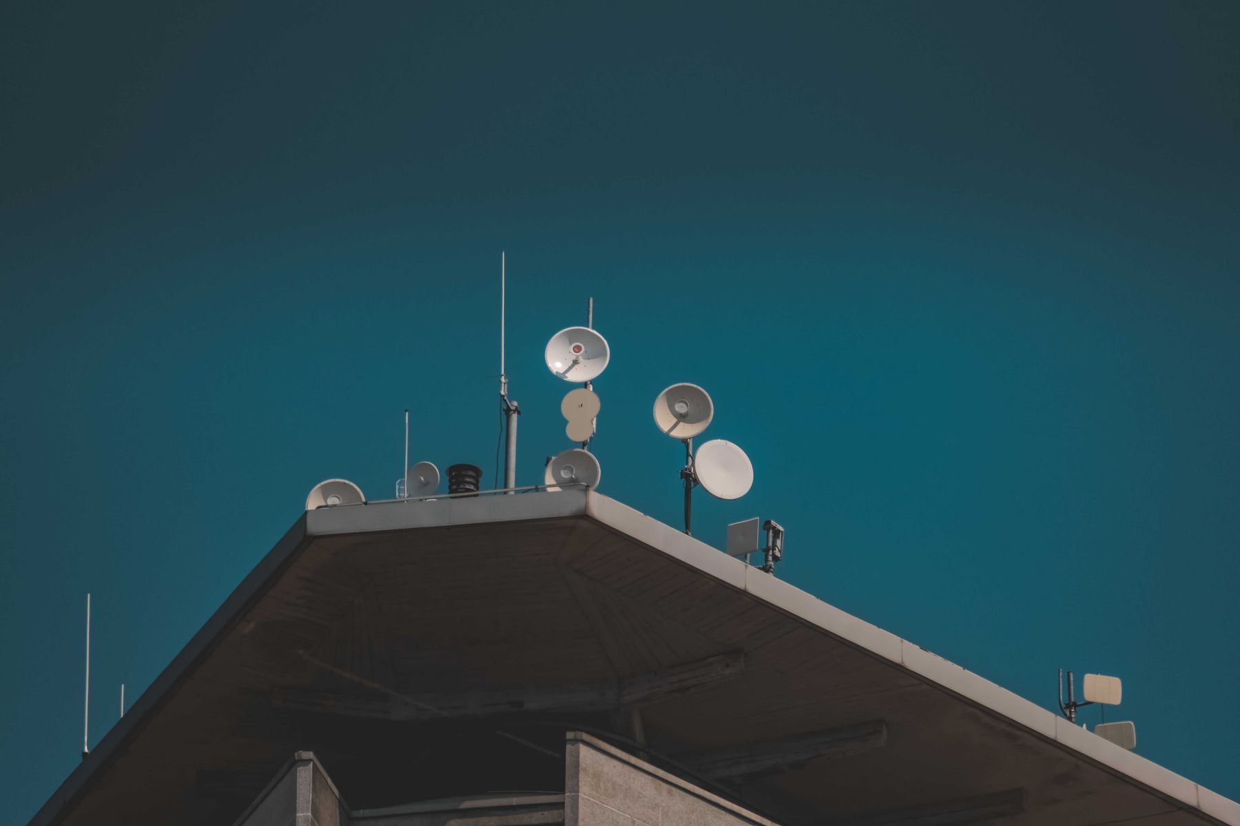 Microwave dish antennas and whip antennas on the corner of a commercial rooftop
